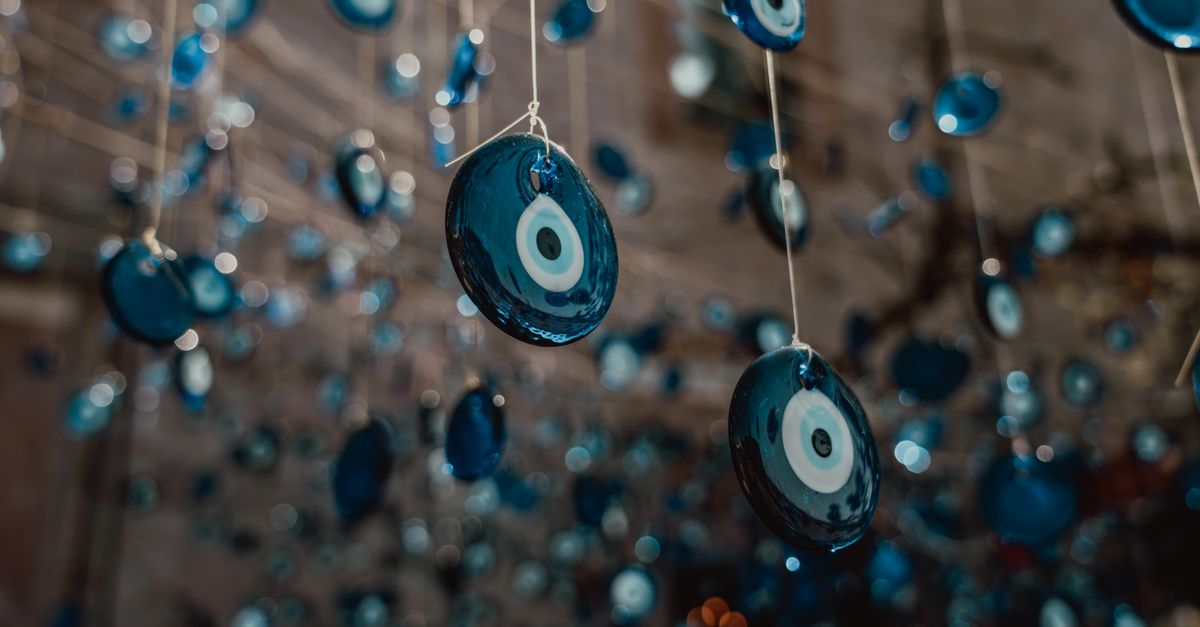 Close-up of numerous blue evil eye charms hanging on strings, capturing tradition and decoration.